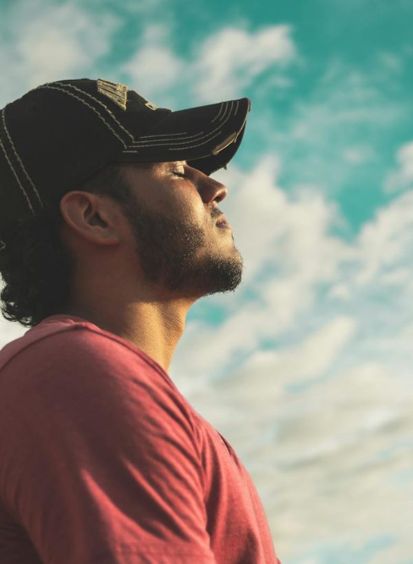 Man Wearing Black Cap With Eyes Closed Under Cloudy Sky